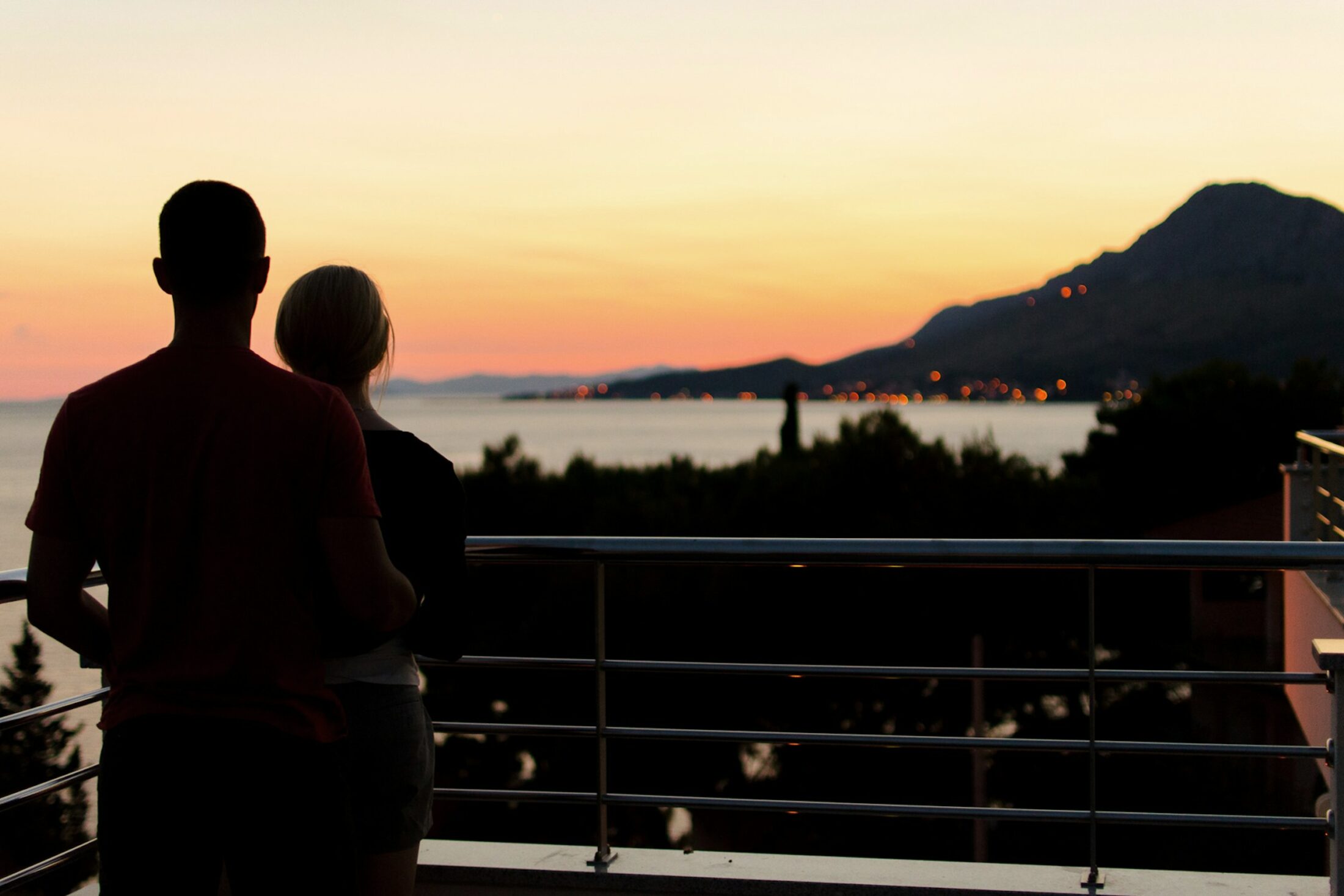 Two people looking out from a terrace at dusk. Illustrative stock photograph, not an Almajour member or property