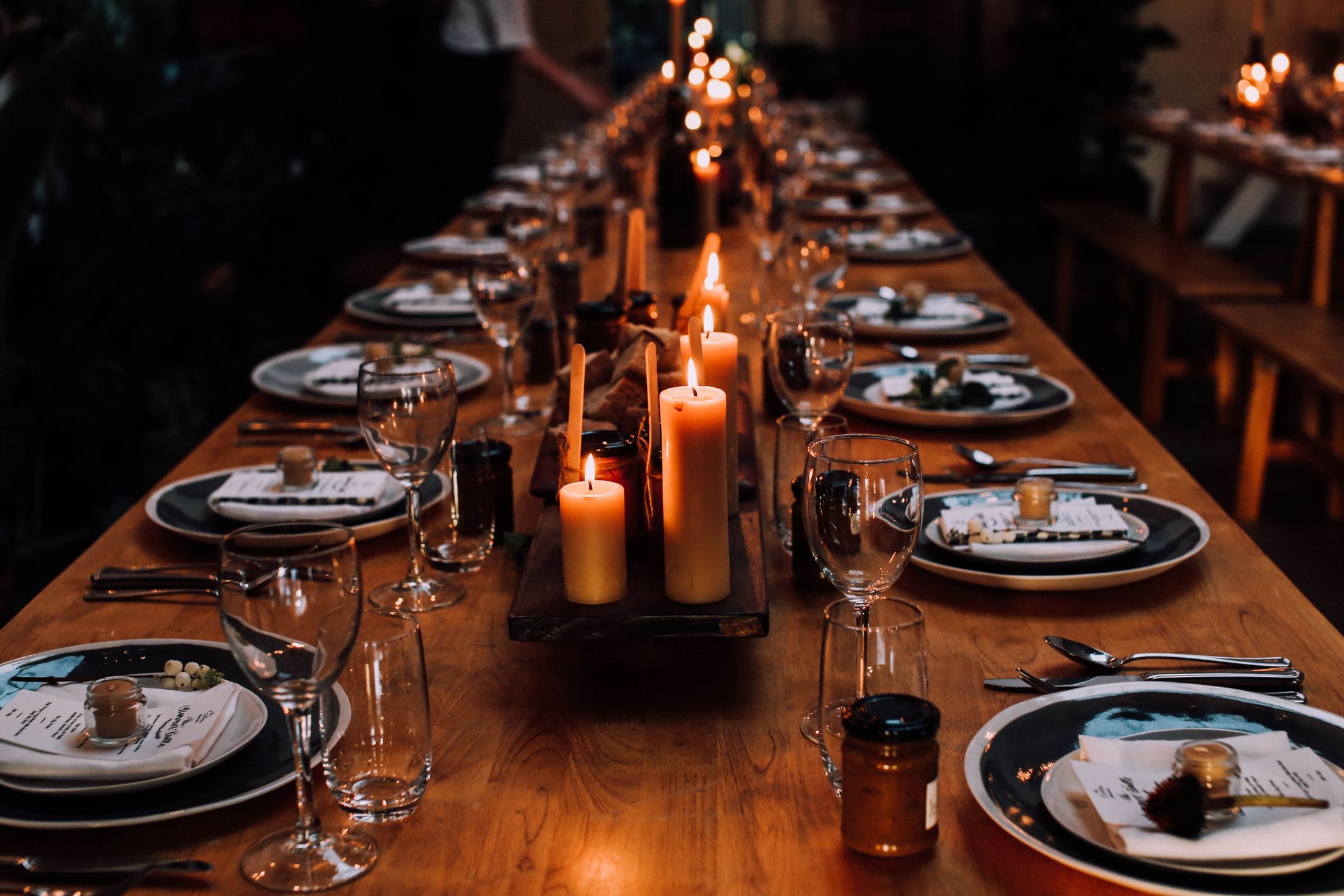 A long wooden table lit by candles and set for a dinner. Illustrative stock photograph, not an Almajour property